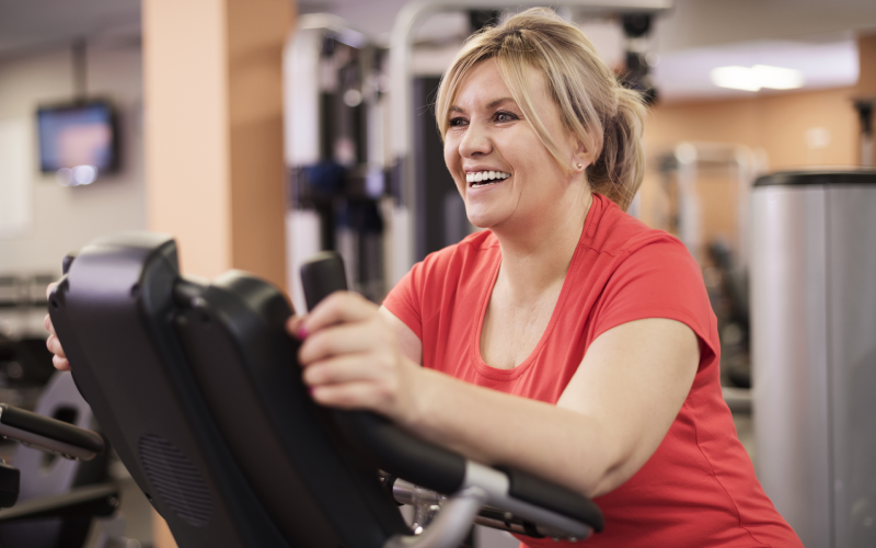 Smiling woman working out on gym machine.